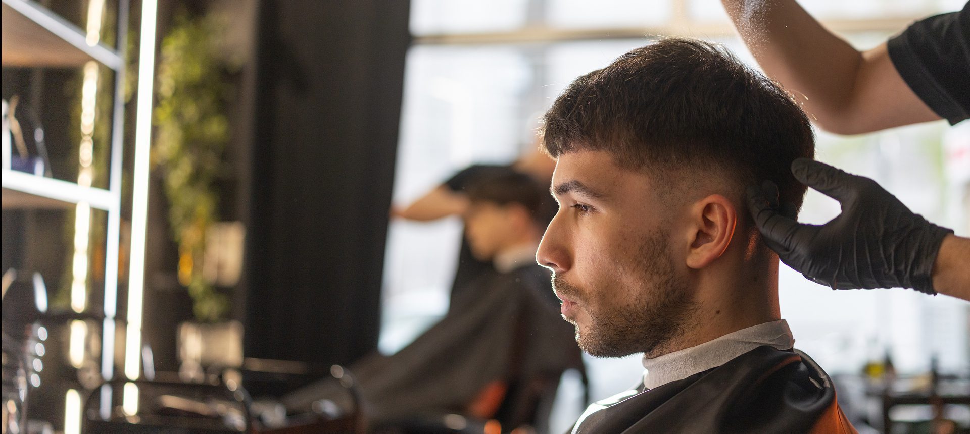 Focused man receiving haircut assistance
