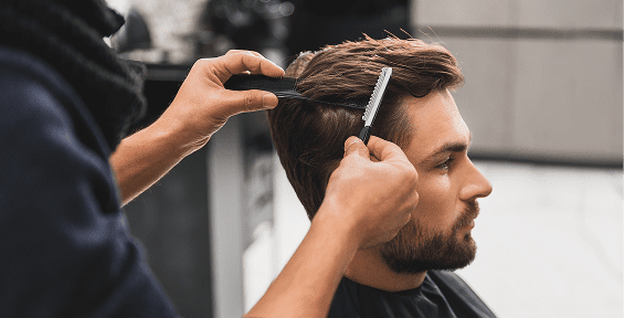 Barber styling client's hair with scissors